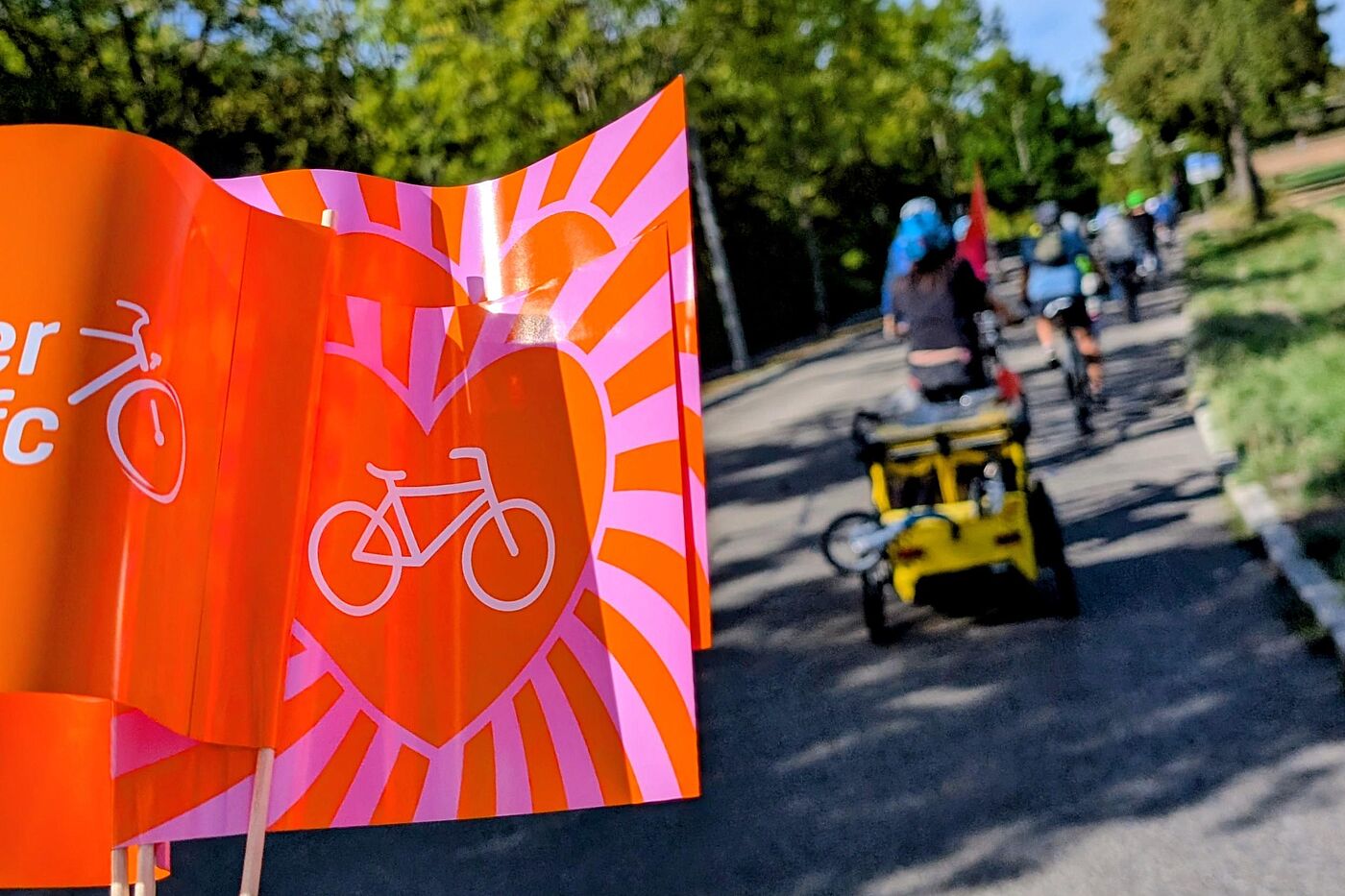 Unterwegs durch Renningen bei der Kidical Mass 2026-09-19 Bunte Fahnen im Vordergrund, im Hintergrund der Demozug auf dem Weg von Renningen nach Malmsheim. Viele kleine und große Menschen auf dem Rad.