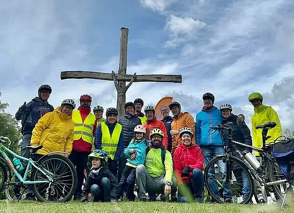Die Gruppe aus Radfahrenden trifft sich vor der gemeinsamen Abfahrt zu einem Gruppenbild am Kreuz auf dem CVJM-Plätzle.